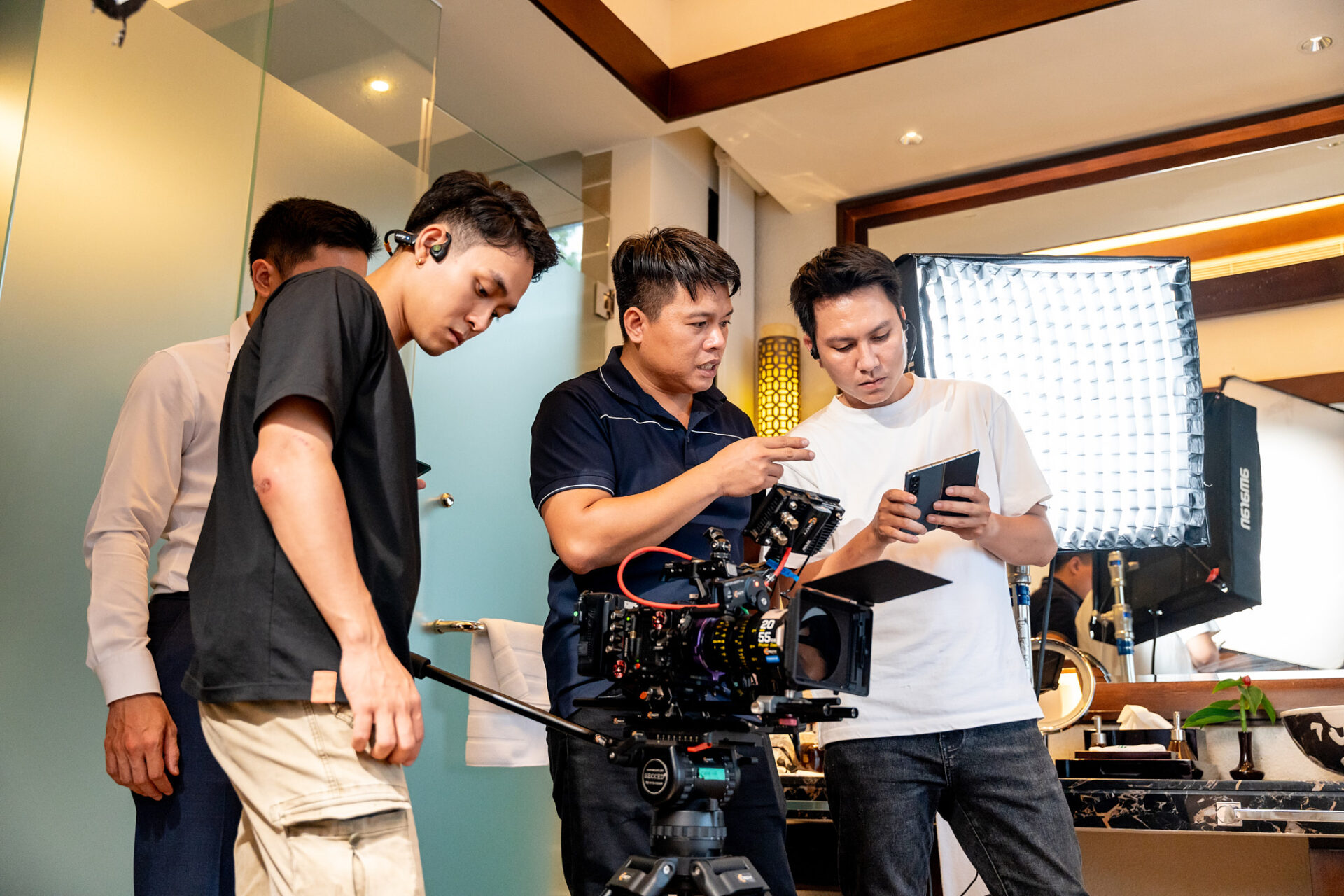 Three CINEFY crew members reviewing the shooting plan on location with an LED light panel behind them.