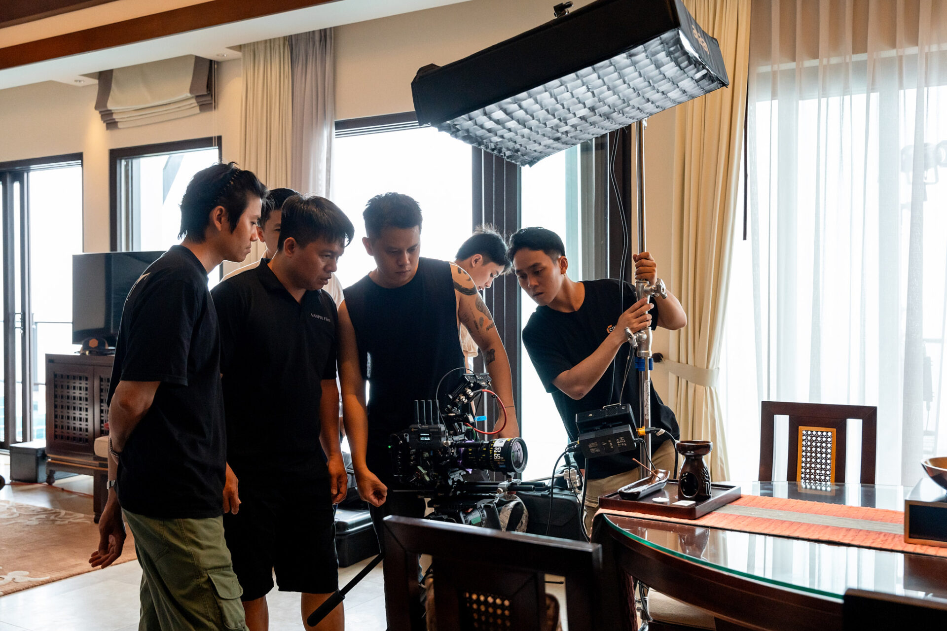 CINEFY crew members gathered around a cinema camera checking the frame during an interior shoot.
