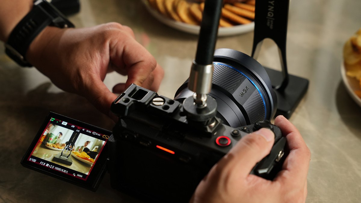 Hands operating a compact camera body with a flip out screen on a video production set in Da Nang