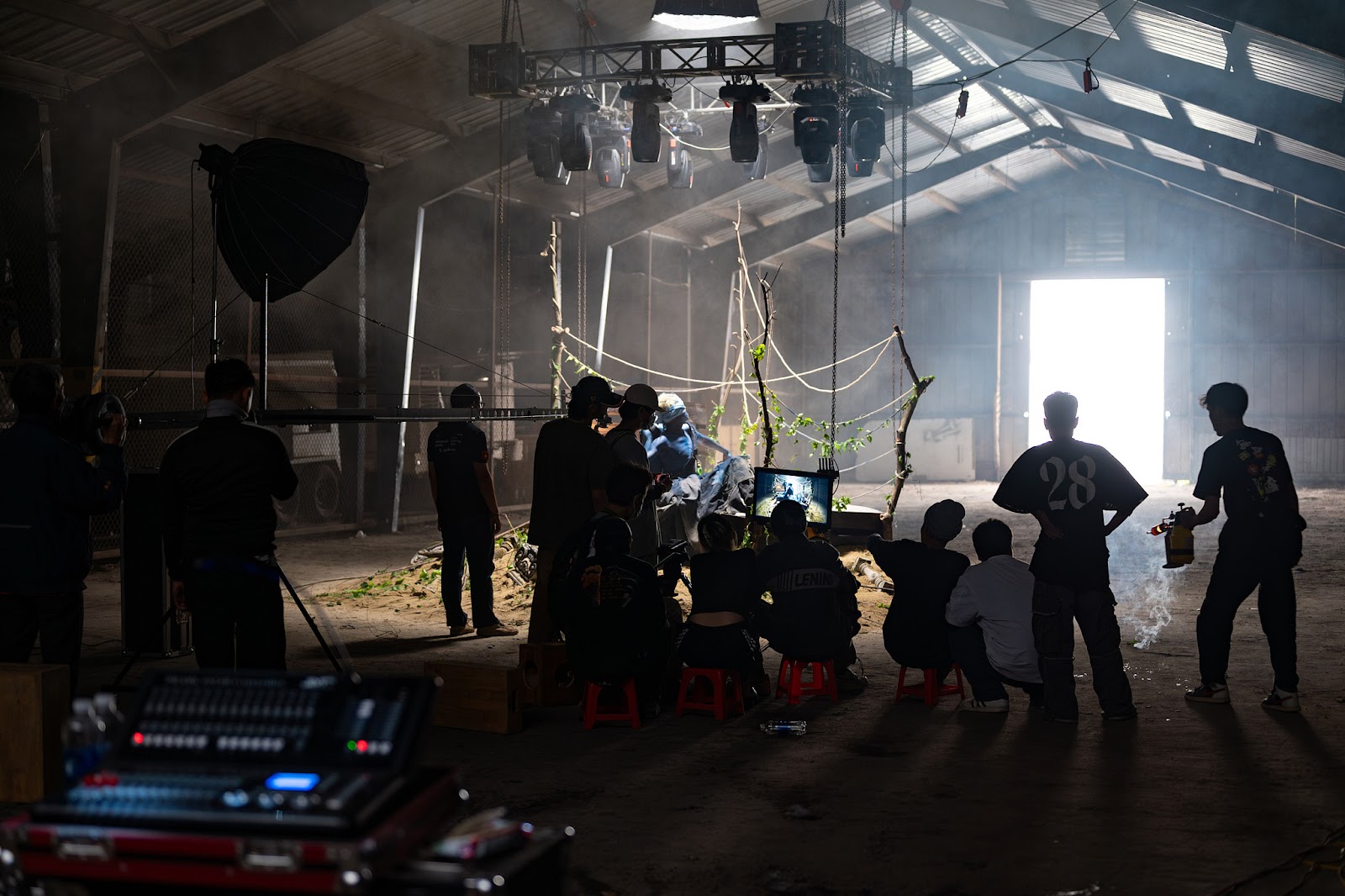 Full crew from a video production company in Da Nang building a large set inside a warehouse with overhead lighting.