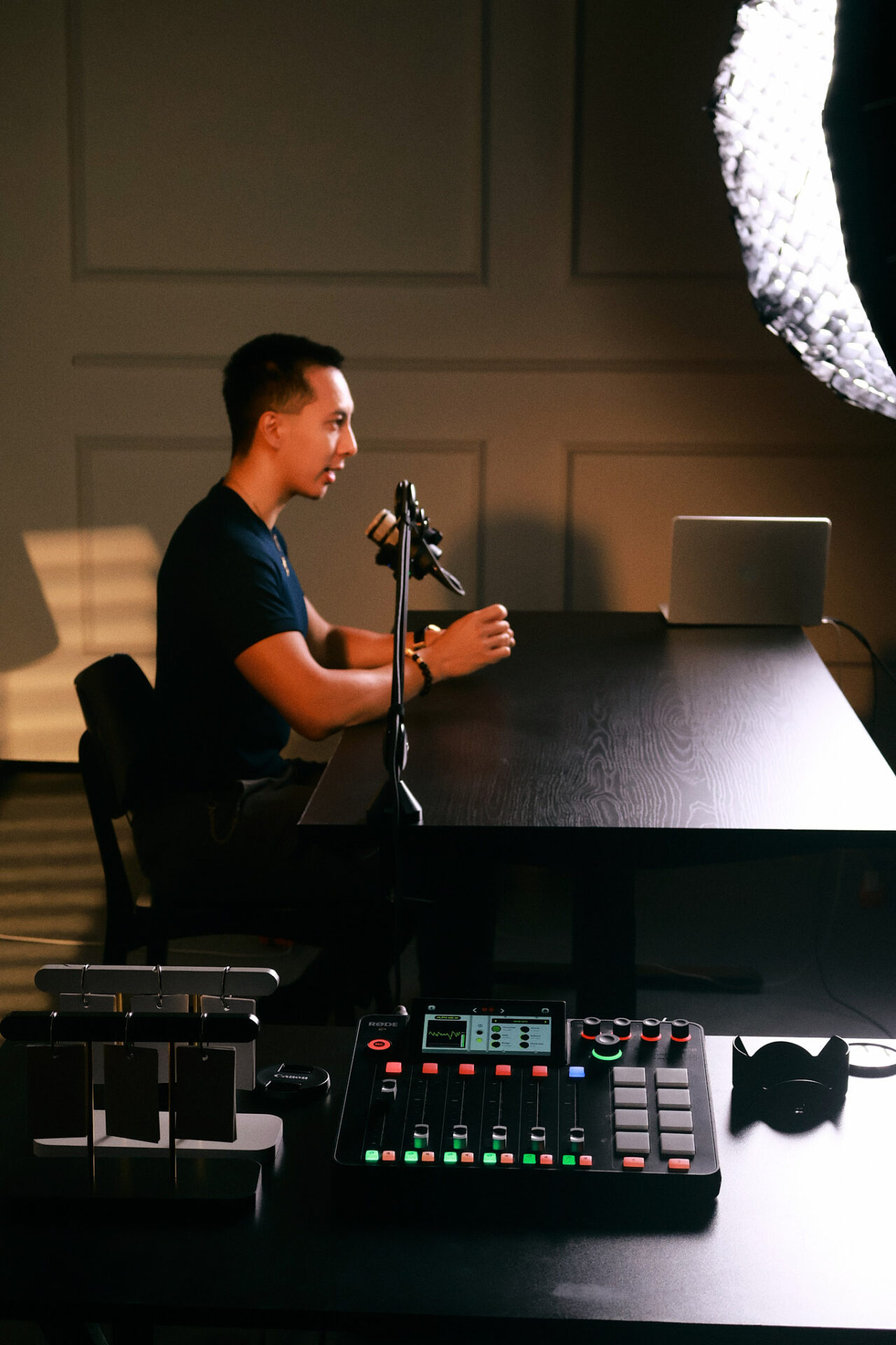 A guest speaking into a boom mounted microphone in the podcast area of the CINEFY studio in Da Nang with a mixer in front