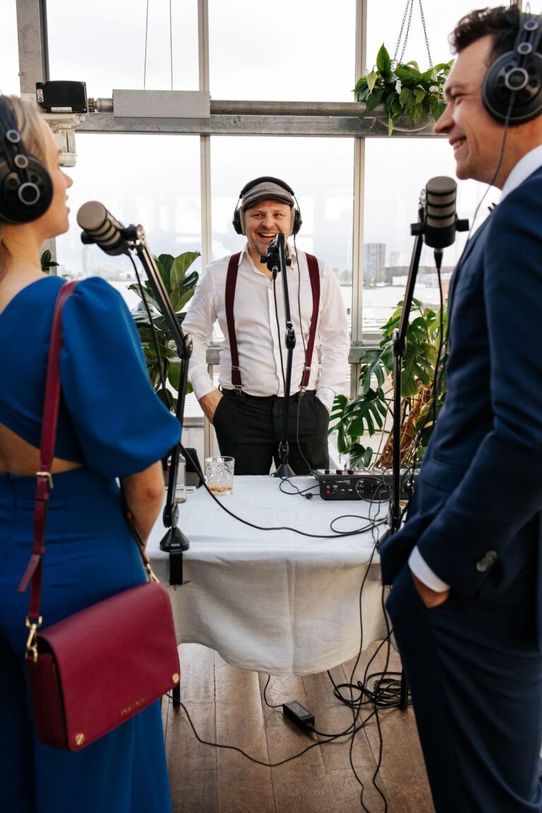 Hai khách mời đeo tai nghe trò chuyện cùng người dẫn chuyện tại góc podcast trong tiệc cưới